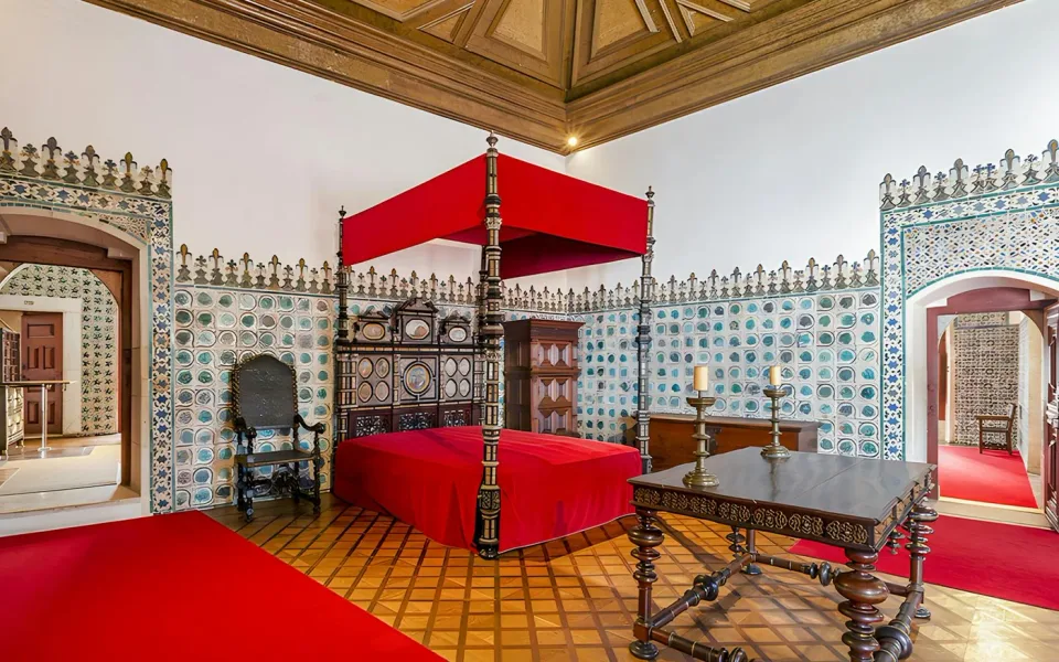 Una cama con dosel rodeada de azulejos con motivos